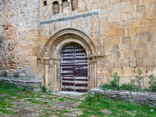 Fototapeta na wymiar Detalle de puerta de iglesia de madera oscura y clara con columnas a los lados y arcos con decoración en Soria, verano de 2021