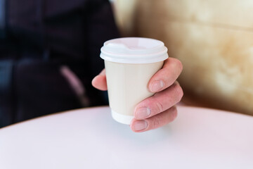 Paper coffee cup in a male hand. Coffee to go. walks in the open air.