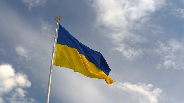 Ukrainian national official flag on flagpole waving in the wind on picturesque sky background