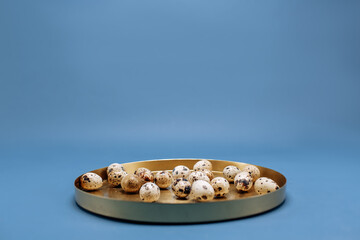 Quail eggs in a golden tray on a blue background