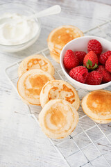 Mini pancake cereal with banana, raspberry, strawberry, honey, yogurt for breakfast. Mini pancake cereal is new trend. Mini pancakes cereal served for breakfast, snack. Selective focus, copy space.