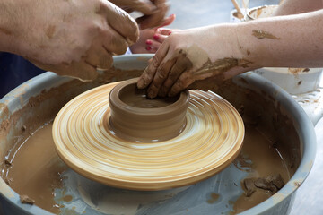 Woman potter teaching the art of pot making. Women working on potters wheel making clay objects. 