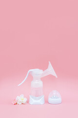 Breast pump and sakura flowers on pink background. Breastfeeding concept. Vertical banner, copy space