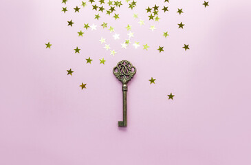 Vintage key decorated with golden stars confetti. The concept of keeping secrets. Сopy space