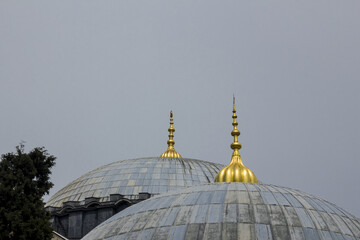 Fototapeta na wymiar Selective focus of two domes of the mosque in the gray sky with copy space