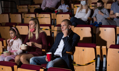 mother, father and their children sitting at film in auditorium during epidemic