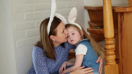 a mother soothes her crying daughter on the wooden stairs of the house. 
