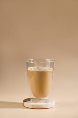 a glass with milk coffee on seamless beige colored background