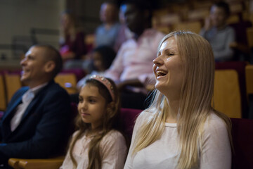 Obraz premium Cheerful family watching a movie and eating popcorn in the cinema. High quality photo