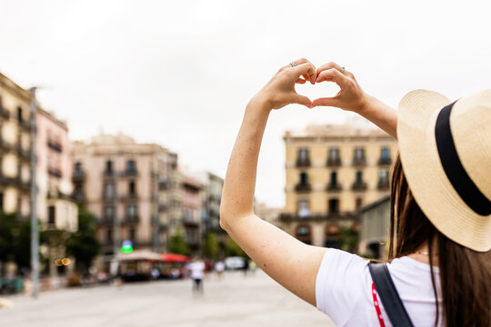 Young woman drawing heart shape with hands in Barcelona city - Travel and summer holidays concept