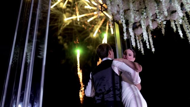 Happy newlyweds dance against the background of fireworks. Wedding couple and fireworks in the night celebrating a new life.