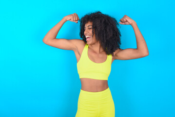 Yes I am winner. Portrait of charming delighted and excited young woman with afro hairstyle in sportswear raising up fist in triumph and victory smiling achieving success grinning from delight.