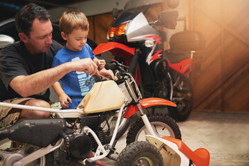Dad is his biggest hero. Shot of a father and son fixing a bike in a garage.