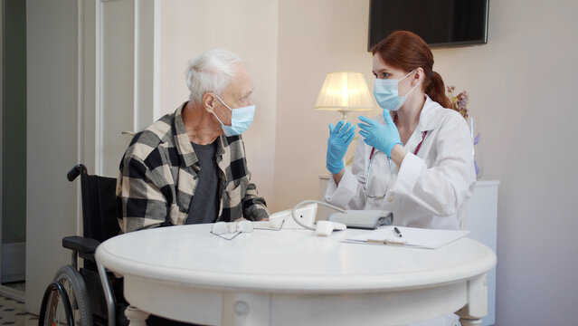 A Doctor Helps An Elderly Disabled Person To Put On A Medical Mask