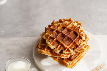 Sweet breakfast - fresh homemade belgian waffles with honey and powdered sugar stacked on white...