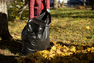 A woman holds a bag of leaves.