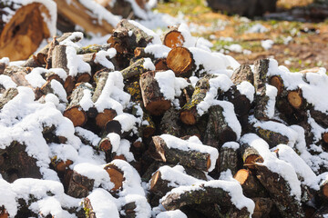 Large firewood stack in winter covered with snow