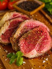 Macro shot. Appetizing juicy meat steaks with spices and green parsley leaves on a wooden background. Meat recipes. Organic food. Restaurant, hotel, home cooking. Advertising, banner.