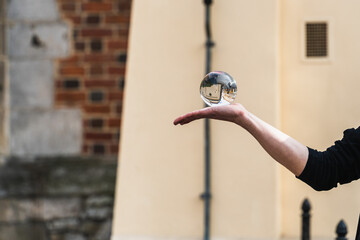 A street performer juggles a transparent acrylic ball that reflects the city on a street in Old...