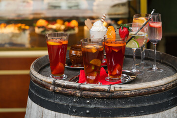 Glasses with cocktails and fruits on a wooden barrel in a street cafe, selective focus