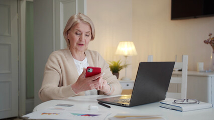 An elderly woman sits at a table and learns to use the phone on her own
