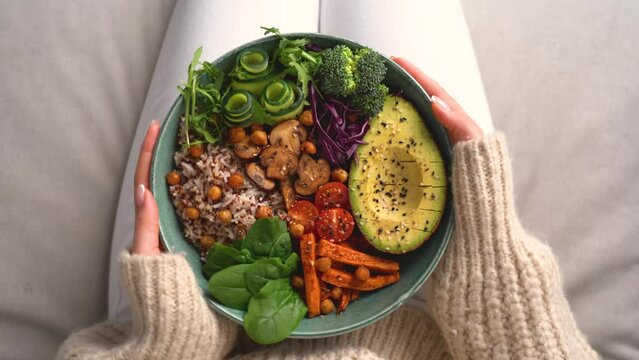 Woman holding plate with vegan or vegetarian food. Buddha bowl with fresh vegetables. Healthy eating