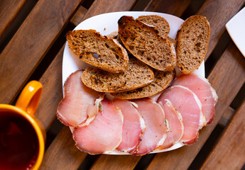 Slices of cured pork tenderloin and bread served on plate.