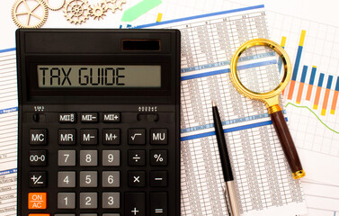 TAX GUIDE is written in the calculator near black-framed glasses and a blue pen.