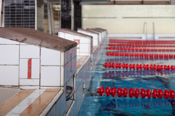 Starting blocks and lanes in a swimming pool. Edge of indoors sport swimming pool. Starting platforms with number 1 for swimming races and competitions. Sport and health concept