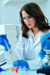 Beautiful young female scientist or researcher working in laboratory with test tube doing some...