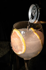 PREPARANDO COCTEL COMPUESTO DE GINEBRA Y AGUA TONICA, CON RODAJAS DE POMELO.