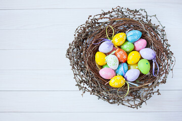 Easter card, nest with decorative colorful eggs on a white wooden background, space for text congratulations