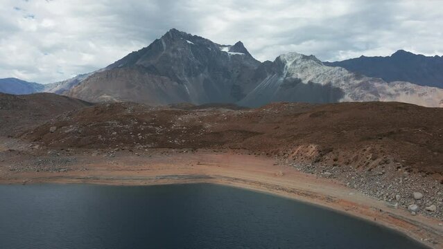 Aerial dolly in of Laguna Negra enclosed between Andean mountains, Meson Alto Hill and Glacier in background, Cajon del Maipo, Chile