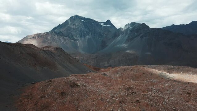 Aerial dolly in of Andean mountain range, Meson Alto Hill and Glacier in background on an overcast day, Cajon del Maipo, Chile