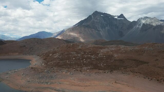 Aerial dolly in of Laguna Negra surrounded by Andean mountains, Meson Alto Hill and Glacier in background, Cajon del Maipo, Chile