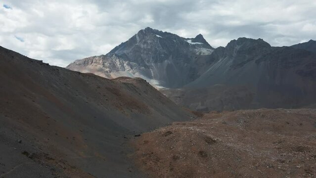 Aerial pan right of Andean mountain range, Meson Alto Hill and Glacier in background on a cloudy day, Cajon del Maipo, Chile