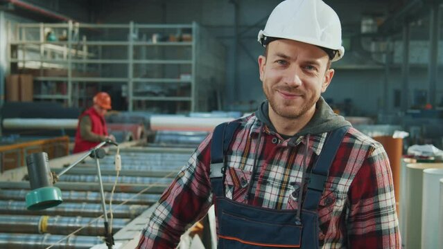Close up portrait industry engineer man wears safety uniform and hard hat stand look at camera smiling in factory. Inspector in warehouse.