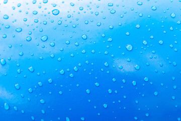 Water drops on blue paint after rain. Blue gradient background or texture. Glare and reflections on water drops. Wallpaper or element for design