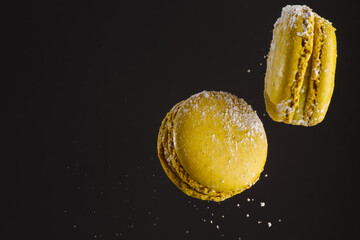 Two yellow french macaroons in a frozen flight on a black background. There are no people in the...