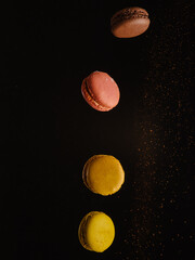 On a black background with chocolate chips French macaroons in a frozen flight. Minimalism. There are no people in the photo. There is free space to insert. Banner. Advertising.