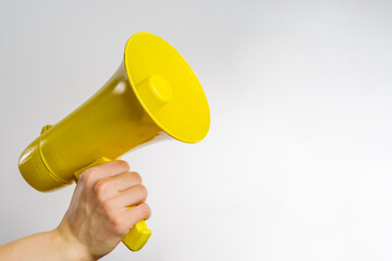 A man's hand is holding a yellow megaphone. Isolated on white background. Symbol of false...