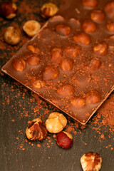 Chocolate bar.Chocolate with hazelnuts and cocoa powder on a black slate background.Chocolate dessert with nuts.