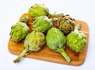 Obraz premium Pile of fresh organic green artichokes on table, ingredients for cooking at home
