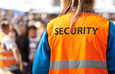 Safety is the main aim. Rearview shot of a security officer standing outdoors with a crowd in the background.