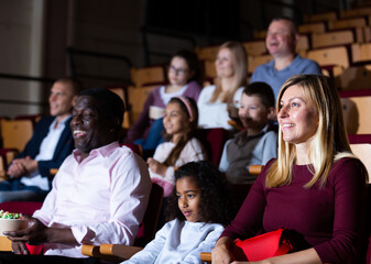 International family enjoys watching comedy in a cinema hall