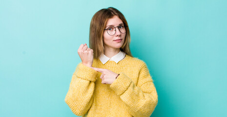 red head pretty woman looking impatient and angry, pointing at watch, asking for punctuality, wants...