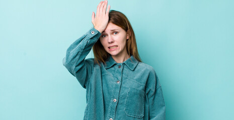 red head pretty woman raising palm to forehead thinking oops, after making a stupid mistake or...