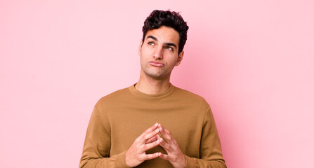 handsome hispanic man scheming and conspiring, thinking devious tricks and cheats, cunning and...