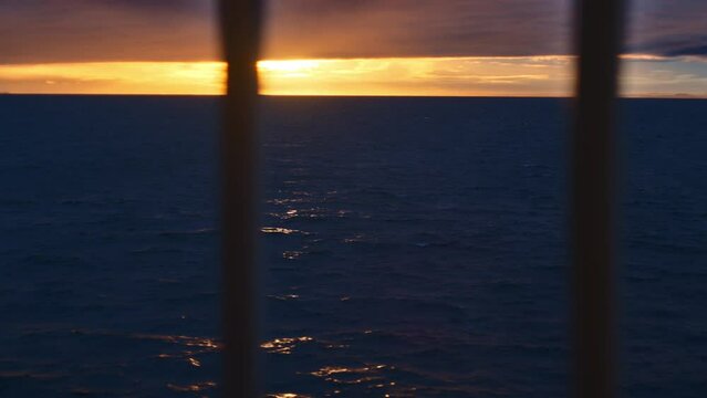 Ferry Moving Across Ocean As Sunsets On Cloudy Horizon