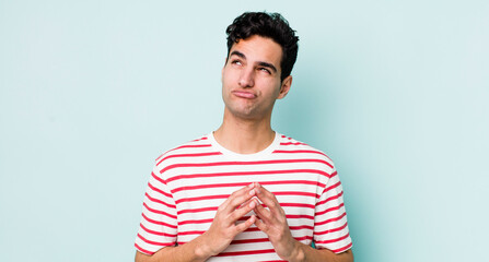 handsome hispanic man scheming and conspiring, thinking devious tricks and cheats, cunning and...